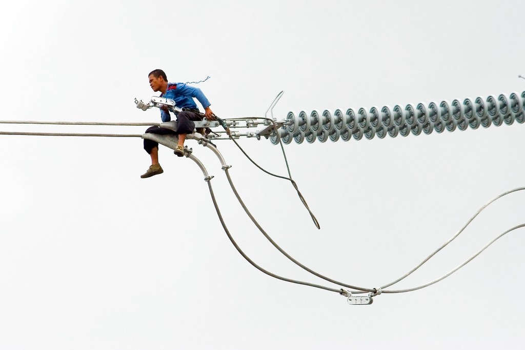 A worker in the Philippines installs a new electric cable atop a pylon. High-tension power lines made of copper are the backbone of electricity infrastructure worldwide.
